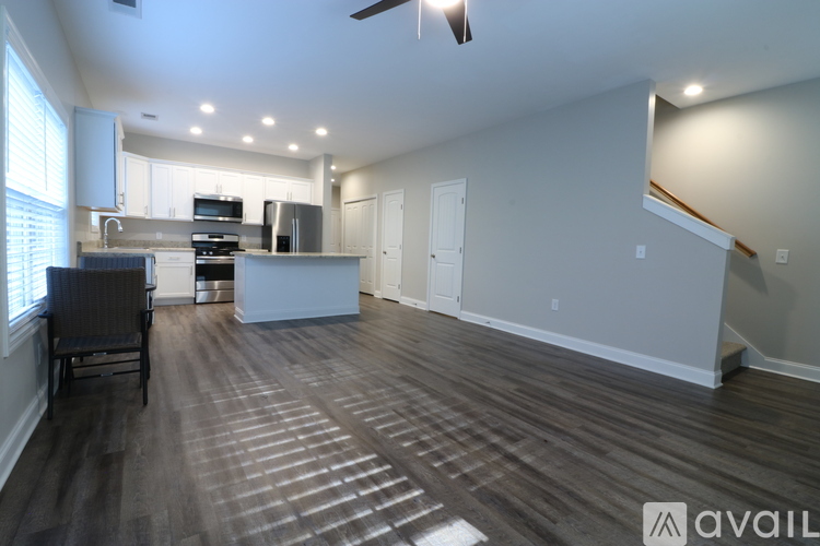 A spacious kitchen and living room with wood flooring and a ceiling fan.