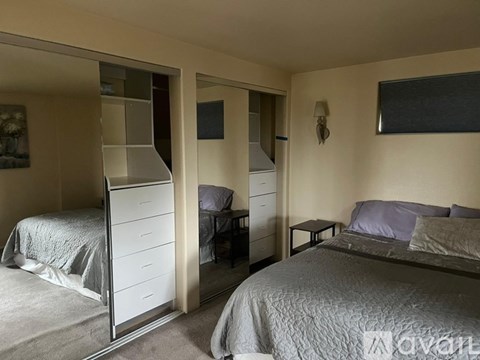 A bedroom with two beds and a mirrored wardrobe.