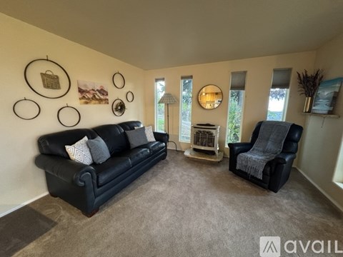 A living room with a black couch, a grey armchair, and a wall decorated with circular frames.