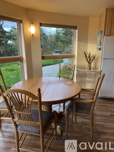 A dining room with a table and chairs and a window overlooking a driveway.