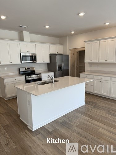 A kitchen with white cabinets and a wooden floor.
