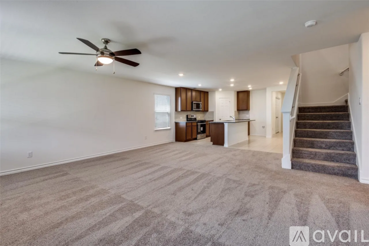 A spacious living room with a carpeted floor and a ceiling fan.