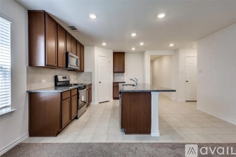 A kitchen with brown cabinets and a black countertop.