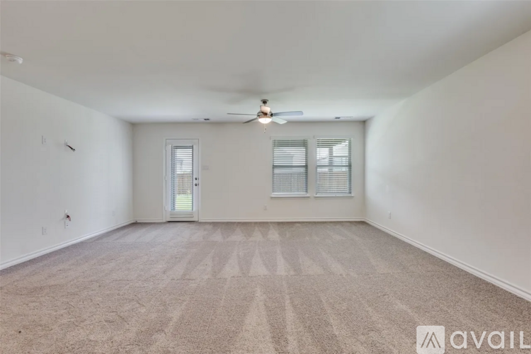 A spacious room with a carpeted floor and a ceiling fan.