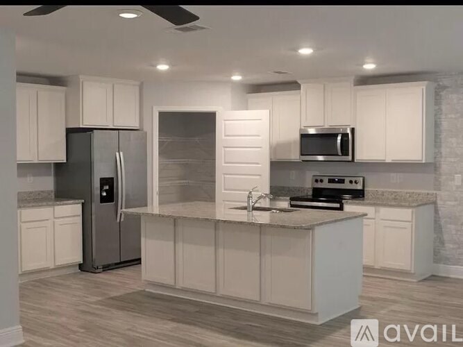 A modern kitchen with white cabinets and stainless steel appliances.