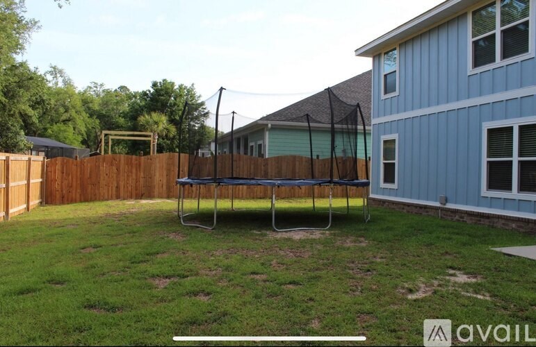 A blue house with a trampoline in the backyard.
