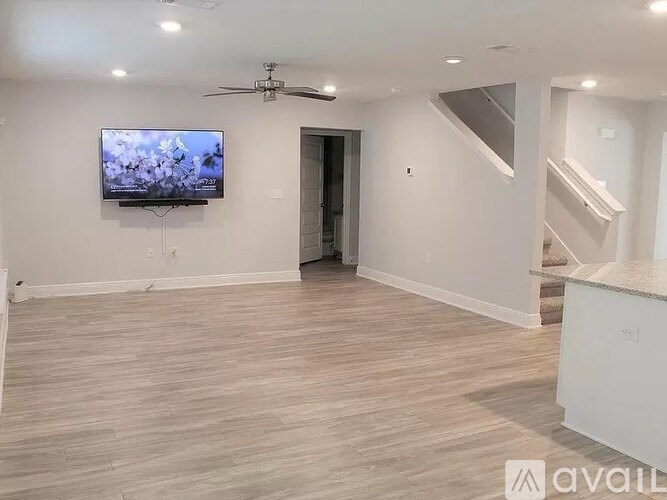 A living room with a television and a ceiling fan.