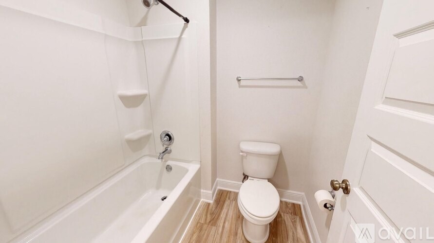 A white bathroom with a toilet, tub, and towel rack.