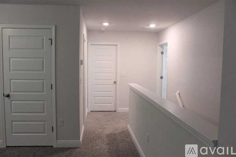 A hallway with a white door and a white wall.