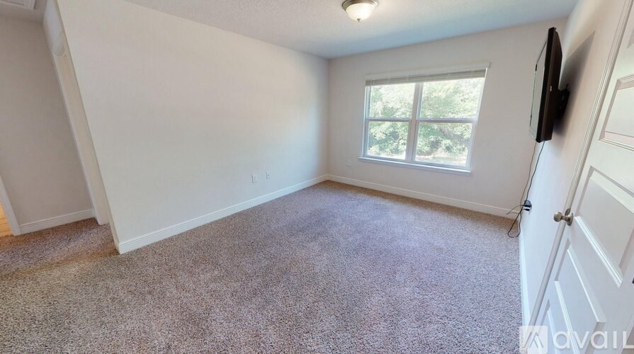 A room with a window and a carpeted floor.