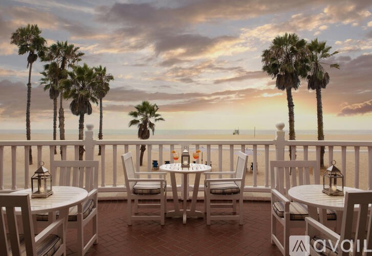A patio with a table set for four overlooks a beach.