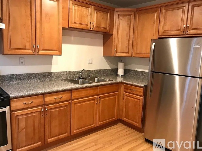 A kitchen with wooden cabinets and a stainless steel refrigerator.