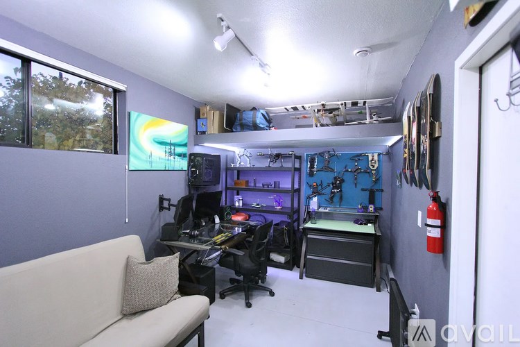 A room with a couch, desk, and computer setup.