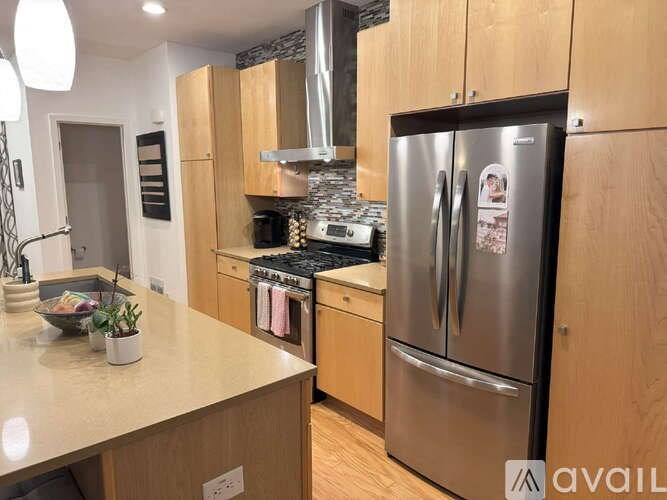 A kitchen with wooden cabinets and a stainless steel refrigerator.