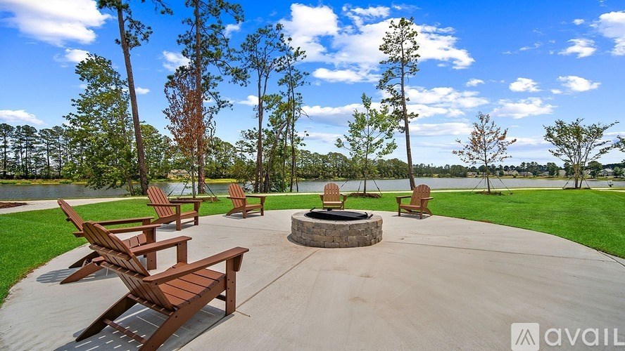 A fire pit is surrounded by wooden chairs in a concrete patio.