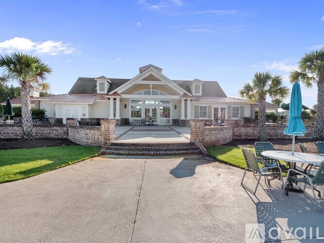 A house with a driveway and a patio with chairs and an umbrella.