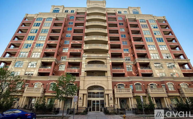 A tall apartment building with a blue car parked in front.