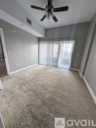 A room with a carpeted floor and a ceiling fan.