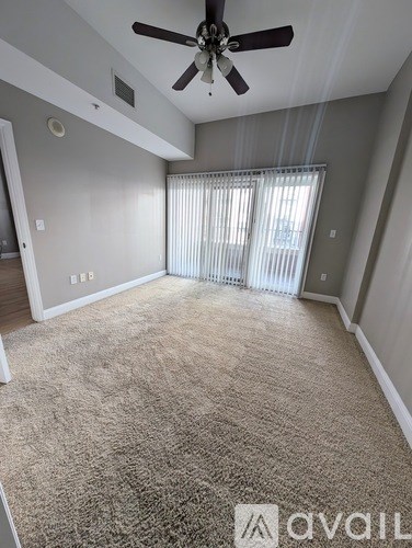 A room with a carpeted floor and a ceiling fan.