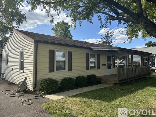 A house with a porch and a tree in front.