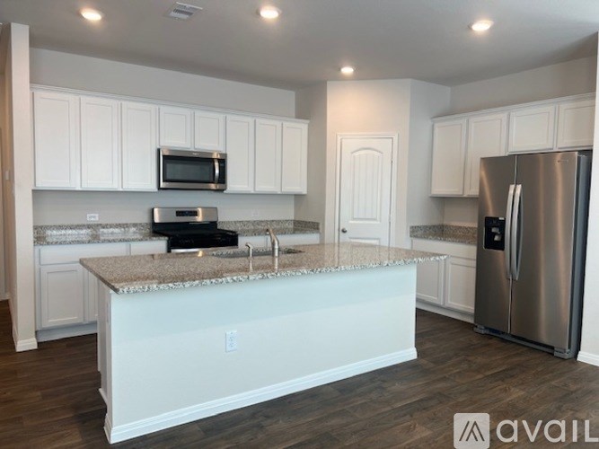 A kitchen with white cabinets and a granite countertop.
