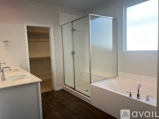 A bathroom with a white sink, a bathtub, and a glass shower door.