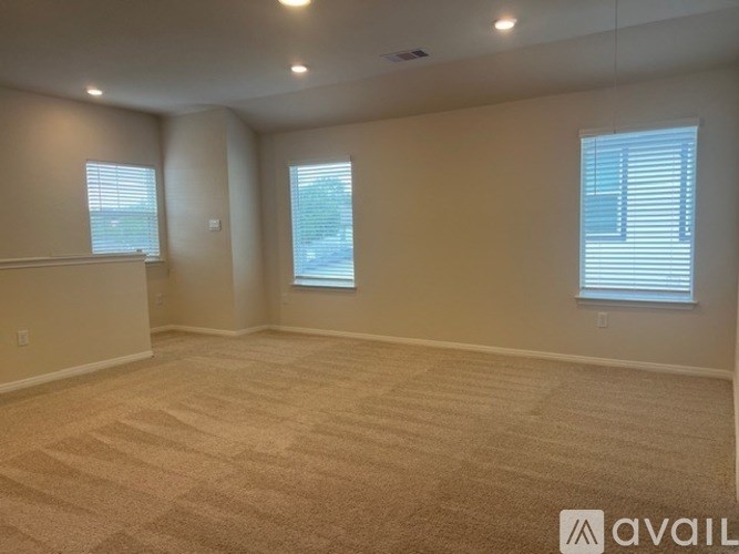 A spacious room with carpeted floor and two windows.