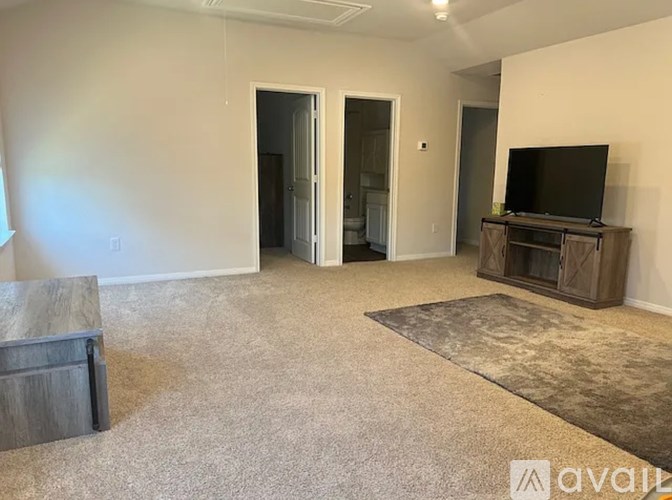 A room with a carpeted floor and a window with blinds.