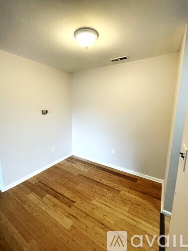 A room with wooden flooring and a white wall.