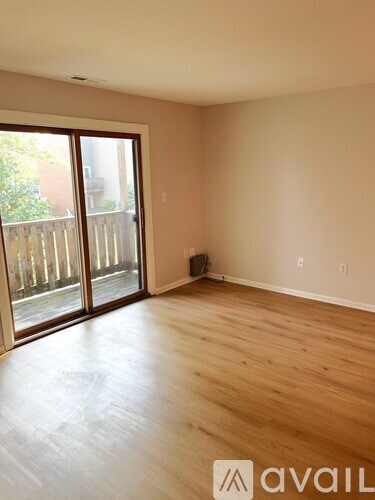 A room with wooden flooring and a sliding glass door leading to a backyard.