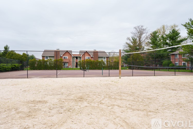 A sandy volleyball court with a net and a residential area in the background.