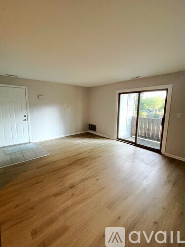A room with wooden flooring and a sliding glass door leading to a balcony.