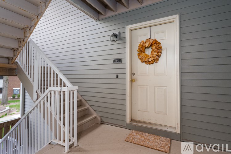 A white door with a wreath on it is on a grey wall.