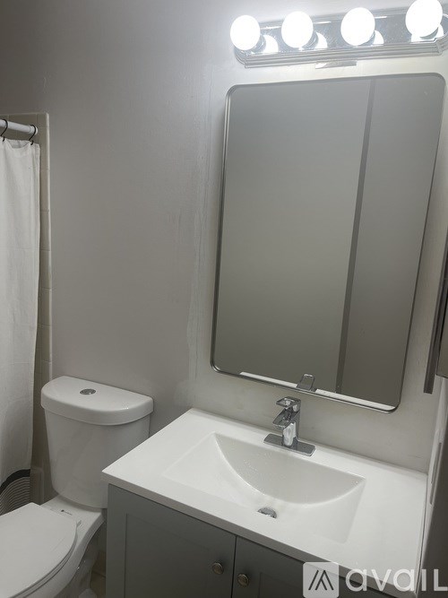 A white sink is under a mirror with lights above it.
