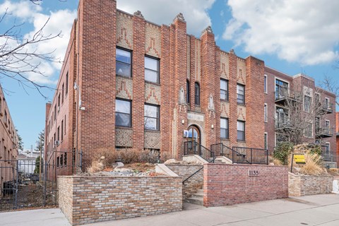 A red brick building with a black iron fence in front.