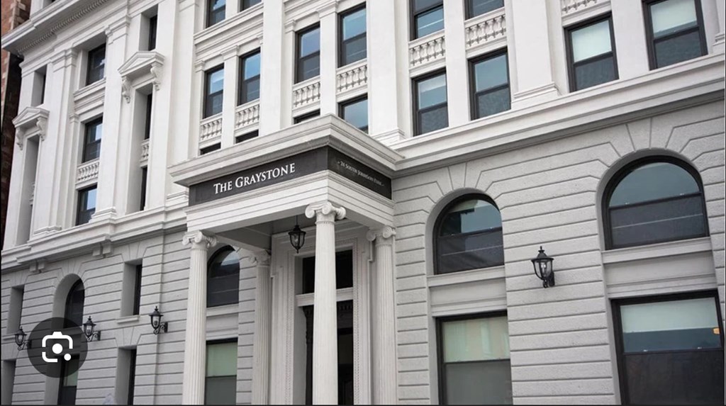 The building is called The Graystone and has a lot of windows.