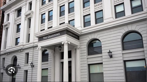 The building is called The Graystone and has a lot of windows.