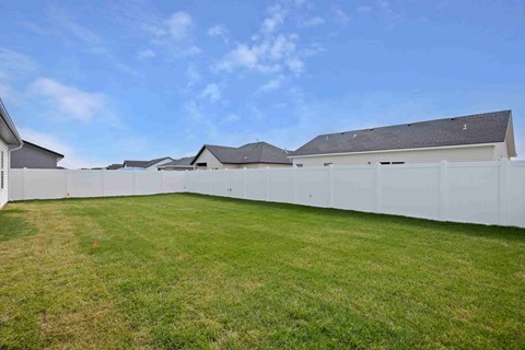 A white fence surrounds a grassy area with houses in the background.