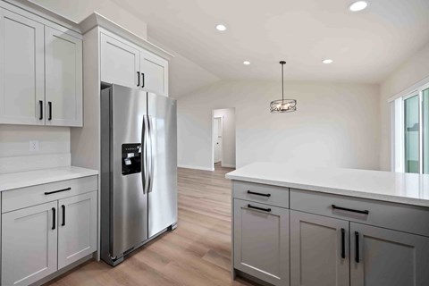 A modern kitchen with a stainless steel refrigerator and white cabinets.