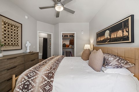 A bedroom with a large bed and a ceiling fan.