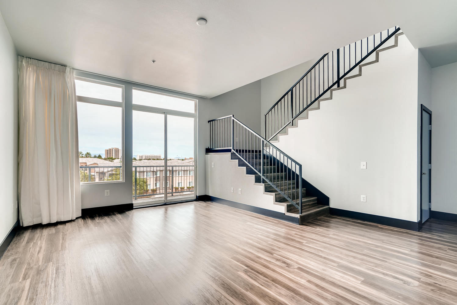 an empty living room with a staircase and a window