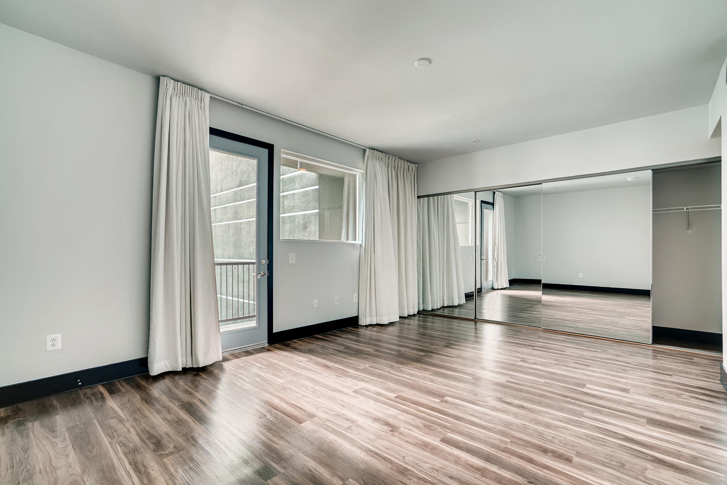 an empty living room with sliding glass doors and wood floors