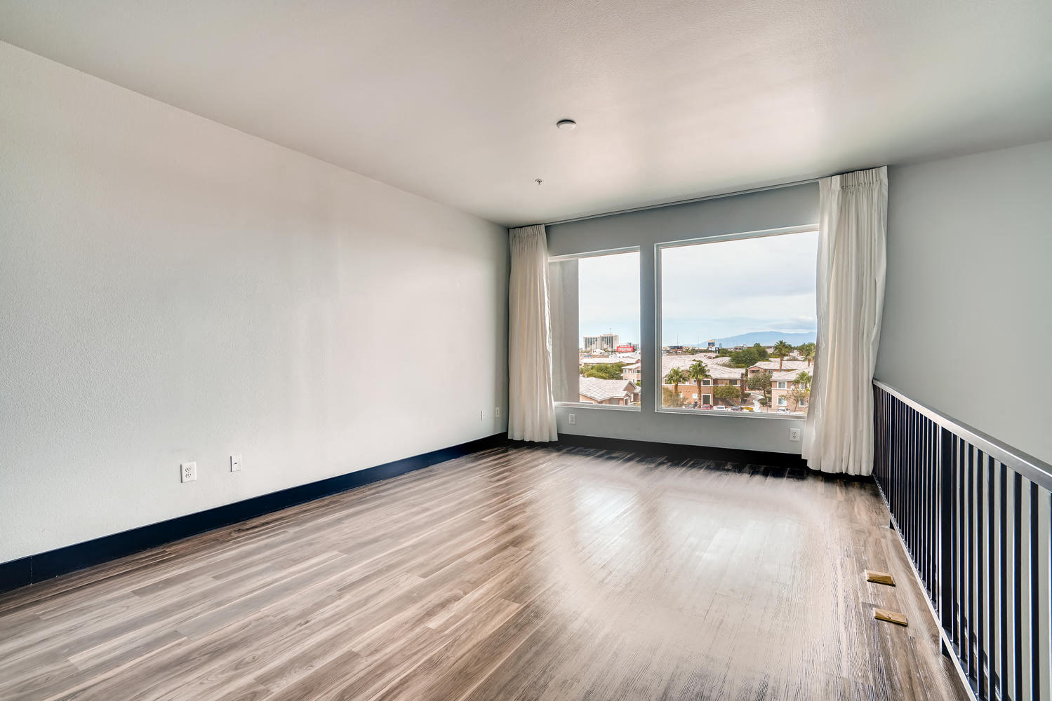 an empty living room with a large window and wood floors