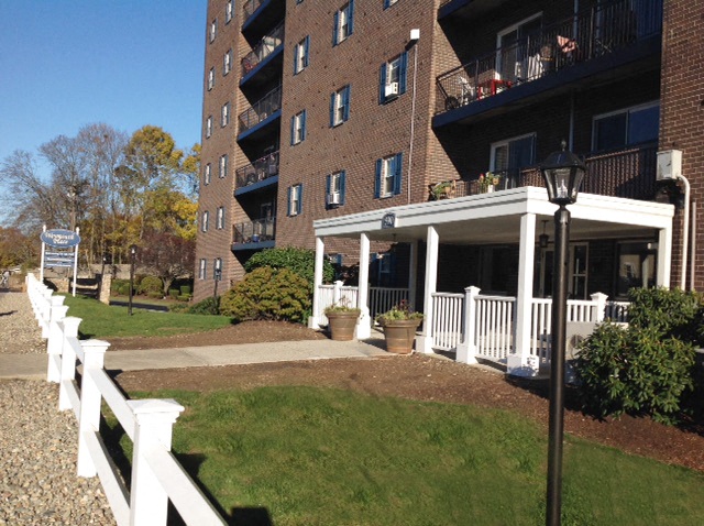 the front porch of an apartment building with a white fence