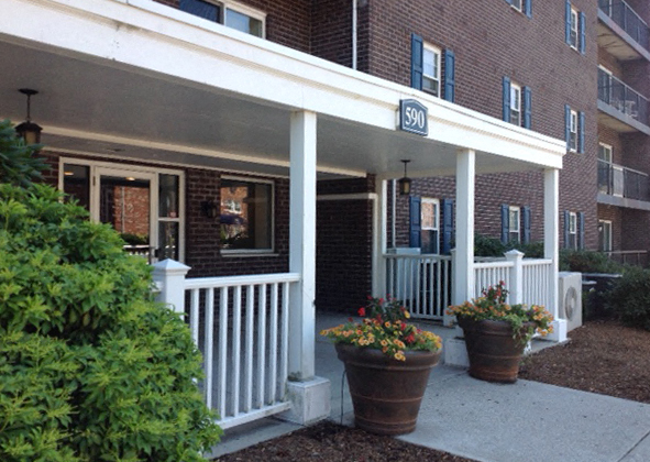 the front porch of an apartment building with potted plants