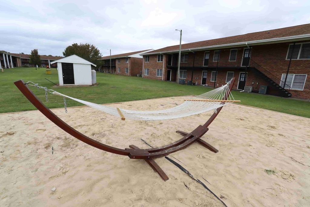 A hammock is strung between two wooden posts in a sandy area.