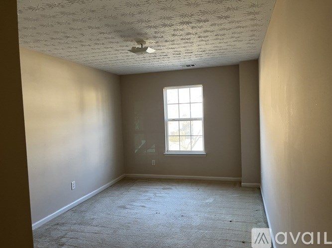 A room with a window and carpeted floor.
