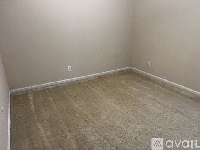 A room with a carpeted floor and a wall socket.