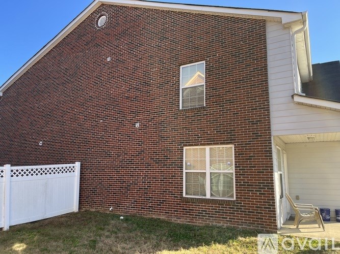 A brick house with a white fence and a small porch.