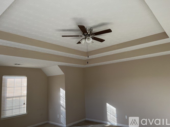 A room with a ceiling fan and two windows.